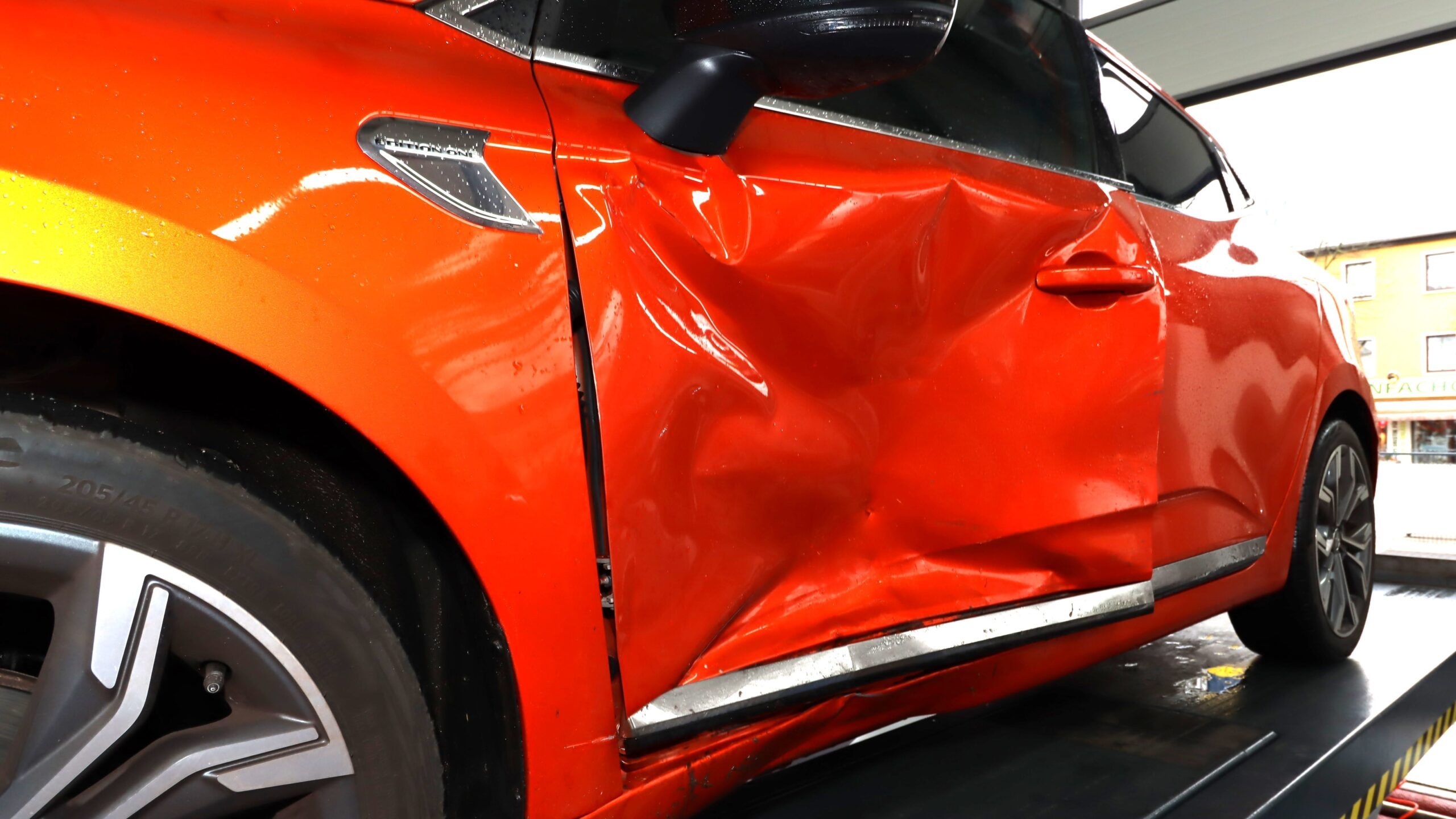 Roter PKW mit deutlichen Unfallschäden an der Seite in KFzmobility-Werkstatt für Gutachtenerstellung