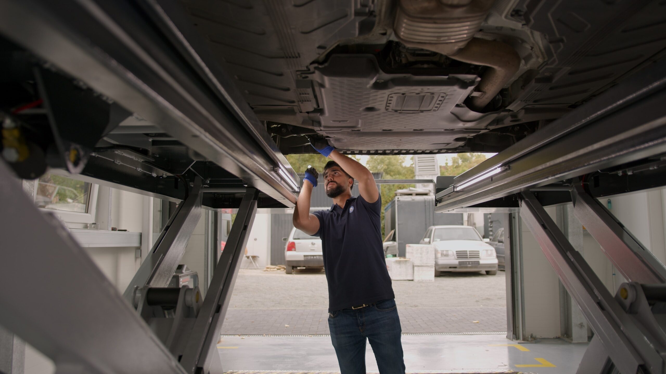 TÜV-Prüfer bei der professionellen Hauptuntersuchung eines Fahrzeugs auf der Hebebühne
